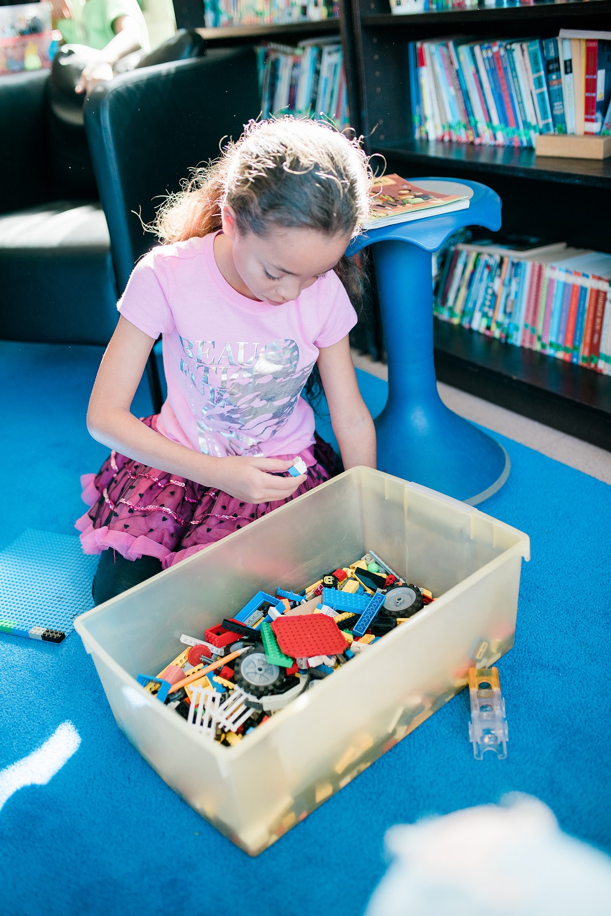 A little girl looks at a box of STEM toys during an open play time.