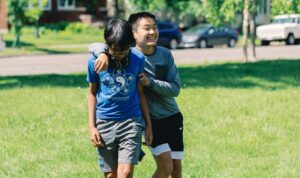 Two Middle school students laugh together during outdoor PE.