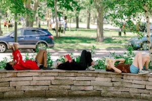 A group of middle school kids read together outside on a beautiful day.